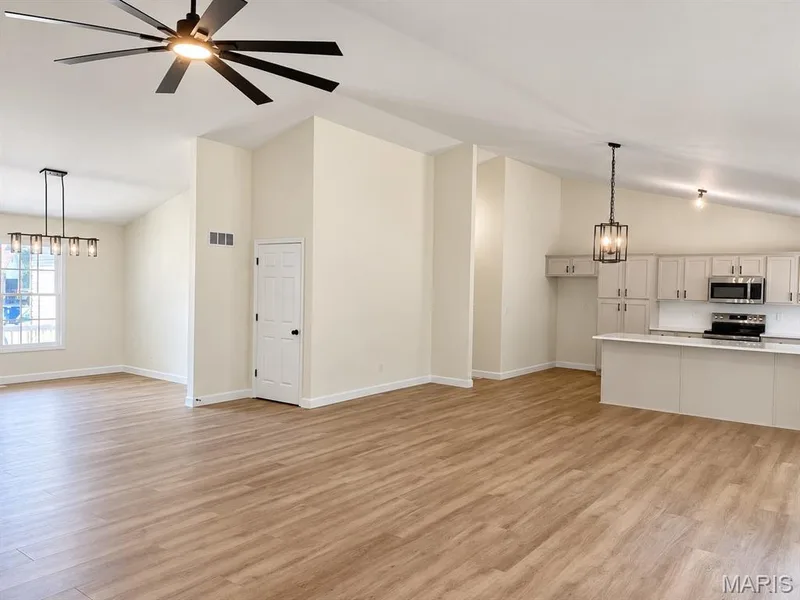 Open-concept living area with wood-finish flooring, vaulted ceilings, and a modern ceiling fan — 1731 Fairview Farms Circle, Wentzville, MO 63385