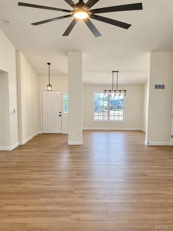 Wood-finish flooring throughout, complemented by a contemporary ceiling fan with integrated lighting, a modern linear chandelier, and a decorative pendant light — 1731 Fairview Farms Circle, Wentzville, MO 63385