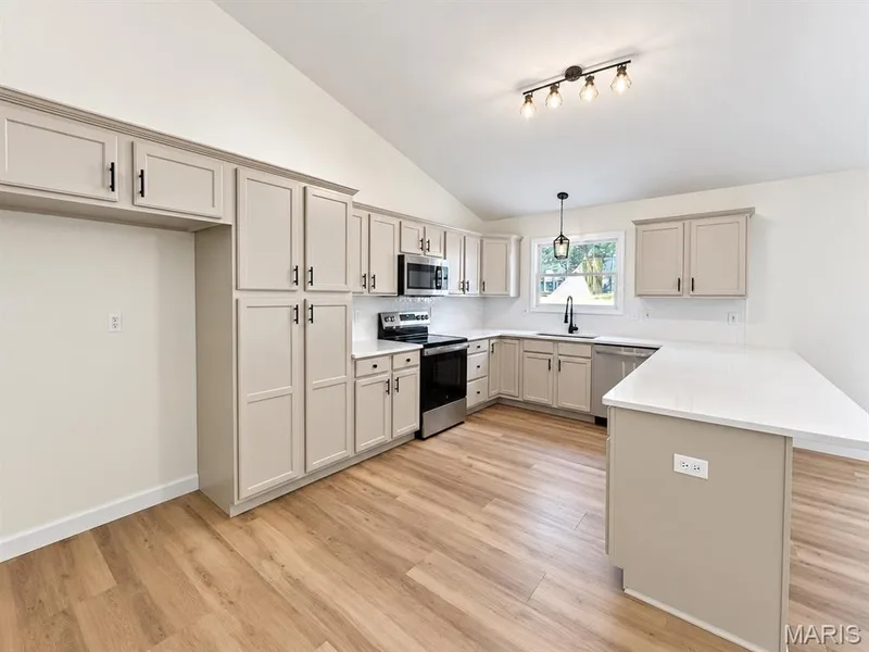 Kitchen featuring light-toned cabinetry, stainless steel appliances, a white subway tile backsplash, and wood-finish flooring — 1731 Fairview Farms Circle, Wentzville, MO 63385