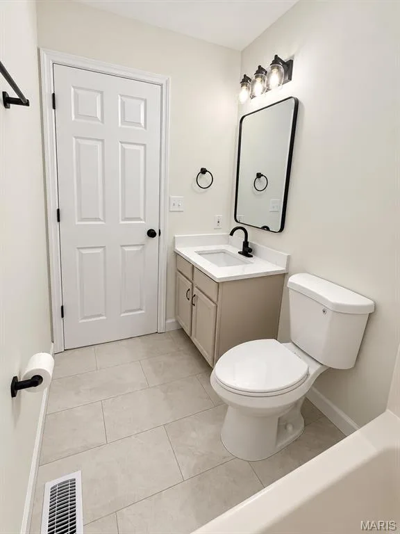 Light-toned floor tiling, neutral vanity with white countertop, black-framed mirror, and modern black fixtures — 1731 Fairview Farms Circle, Wentzville, MO 63385