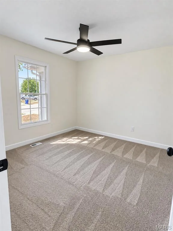 Spacious room featuring neutral carpet flooring, a modern black ceiling fan with integrated lighting, and a double-hung window — 1731 Fairview Farms Circle, Wentzville, MO 63385
