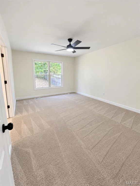 Spacious room featuring neutral carpeting, a dual-pane window, and a ceiling fan with integrated lighting — 1731 Fairview Farms Circle, Wentzville, MO 63385