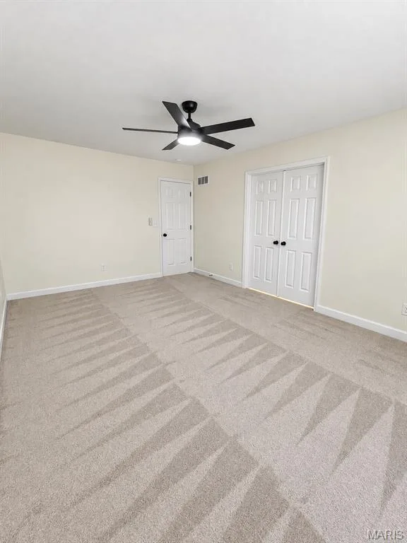 Textured carpet flooring, ceiling fan with integrated lighting, white paneled doors, and neutral wall tones — 1731 Fairview Farms Circle, Wentzville, MO 63385