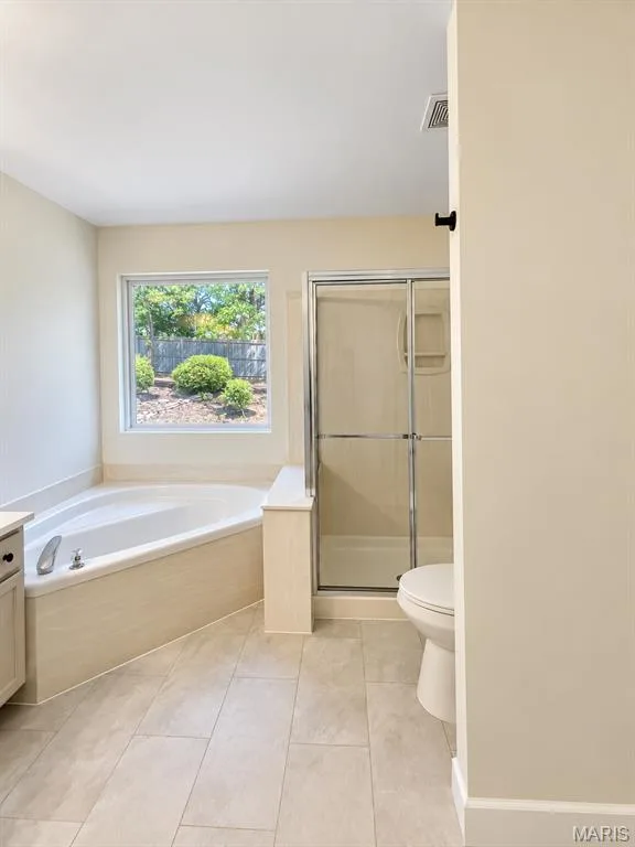 Corner soaking tub, separate shower with glass enclosure, single window, and light-toned tile flooring — 1731 Fairview Farms Circle, Wentzville, MO 63385