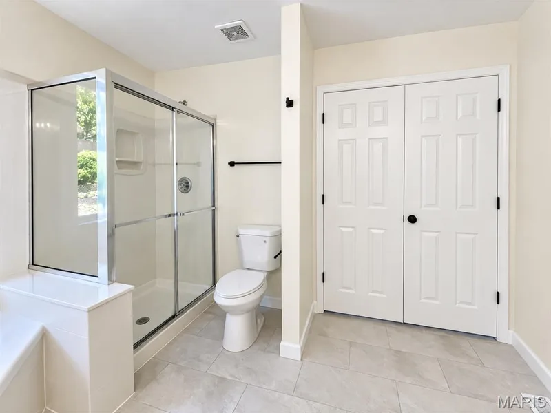 Walk-in shower with sliding glass enclosure, integrated shelving, and polished chrome fixtures — 1731 Fairview Farms Circle, Wentzville, MO 63385