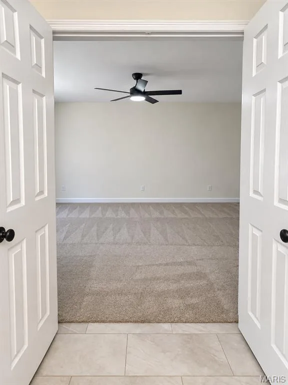 Double panel doors opening into a room featuring carpet flooring, a ceiling fan with integrated lighting, and crown molding — 1731 Fairview Farms Circle, Wentzville, MO 63385