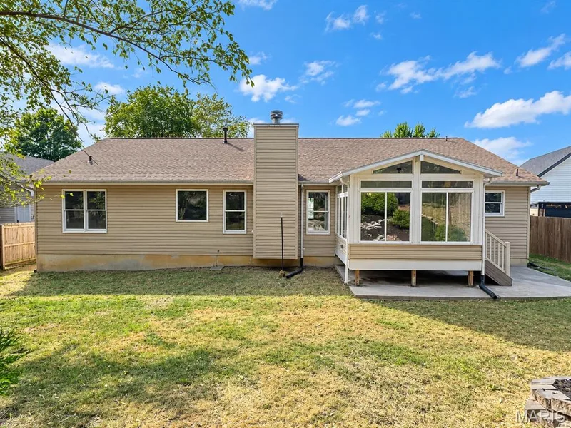 Expansive rear exterior featuring a sunroom addition, concrete patio, and a fenced perimeter — 1731 Fairview Farms Circle, Wentzville, MO 63385