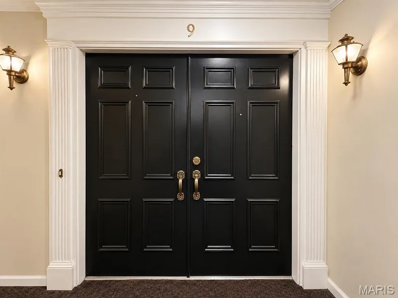 Double paneled entry doors with brass hardware, fluted pilasters, a decorative transom, and brass wall sconces — 15631 Hedgeford Court #9, Chesterfield, MO 63017
