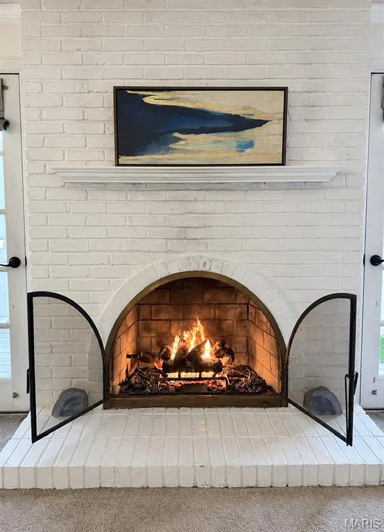 White-painted brick fireplace featuring an arched firebox, a classic mantel, and a brick hearth — 15631 Hedgeford Court #9, Chesterfield, MO 63017