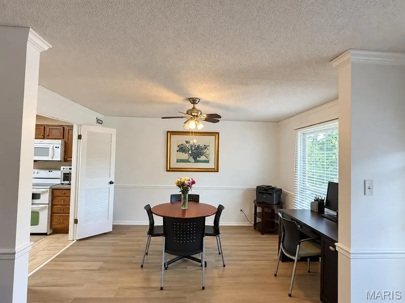 Wood-finish flooring throughout, crown molding, chair rail detailing, ceiling fan with light fixture, and window with blinds — 15631 Hedgeford Court #9, Chesterfield, MO 63017