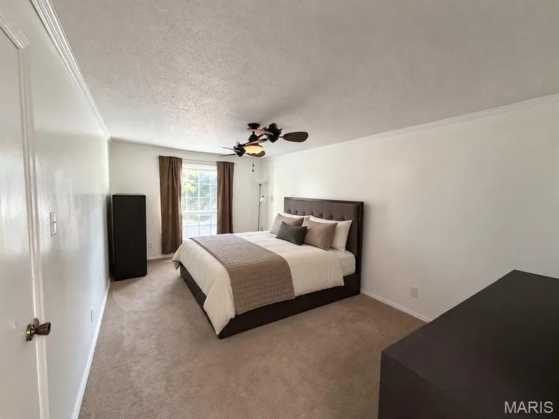 Carpeted room featuring a ceiling fan, crown molding, and a window with window treatments — 15631 Hedgeford Court #9, Chesterfield, MO 63017