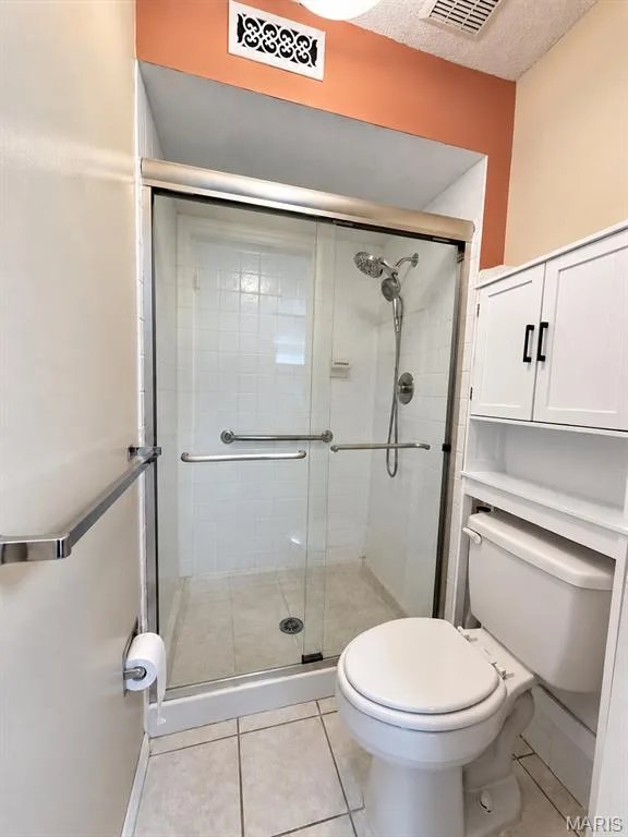 Glass-enclosed shower with a multi-function showerhead, tiled walls, and grab bars — 15631 Hedgeford Court #9, Chesterfield, MO 63017