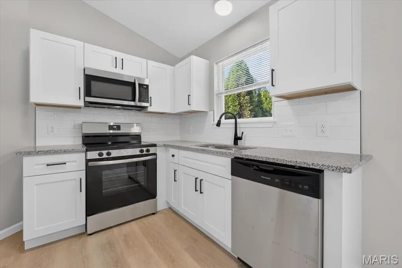 Kitchen features solid counters, soft close cabinetry and tile backsplash — 1540 Batters Box Drive, O'Fallon, MO 63366