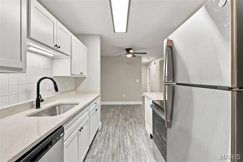Kitchen featuring white cabinetry, light countertops, subway tile backsplash, stainless steel appliances, and wood-finish flooring — 2415 Sandalwood Creek Court #C, Wildwood, MO 63038