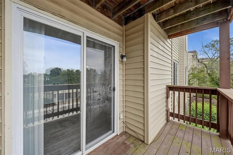 Outdoor balcony featuring wood decking, wood railings, and a sliding glass door — 2415 Sandalwood Creek Court #C, Wildwood, MO 63038