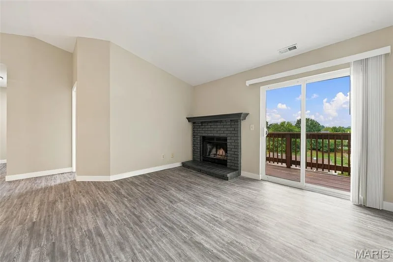 Spacious Living Room features wood burning fireplace and sliding door to private deck. — 2415 Sandalwood Creek Court #E, Wildwood, MO 63038