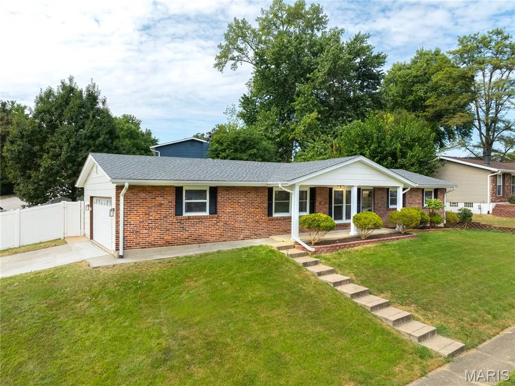 Brick exterior with white trim, covered front porch, integrated single-car garage, and concrete driveway — 3025 Sherwood Lane, St Charles, MO 63301