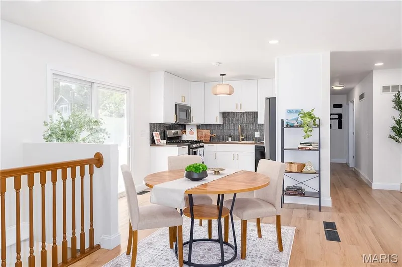 Kitchen featuring white cabinetry with gold-toned hardware, dark tile backsplash, and stainless steel appliances — 3025 Sherwood Lane, St Charles, MO 63301