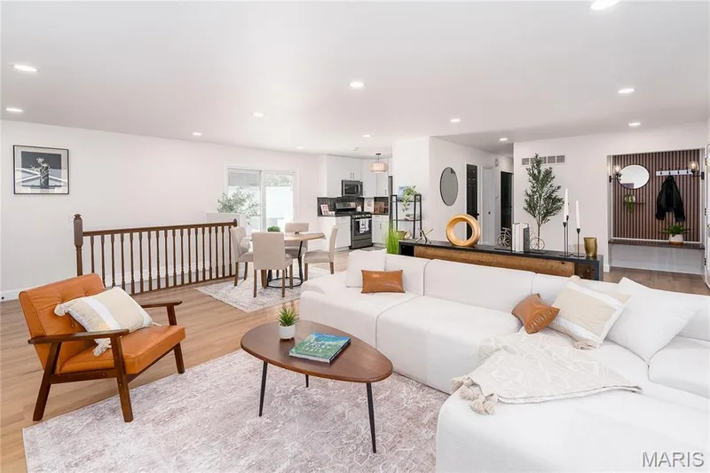Open-concept living space with wood-finish flooring, recessed lighting, and a built-in entryway bench with slat wall detailing — 3025 Sherwood Lane, St Charles, MO 63301