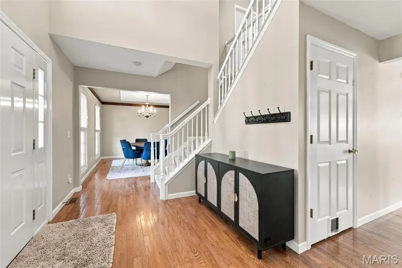 Wood-finish flooring throughout, white paneled doors, and a staircase with white balusters — 8 Jacobs Place Court, O'Fallon, MO 63376
