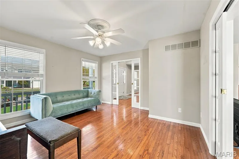 Hardwood-finish flooring, white ceiling fan, multiple windows, light-colored wall paint, and white trim — 8 Jacobs Place Court, O'Fallon, MO 63376