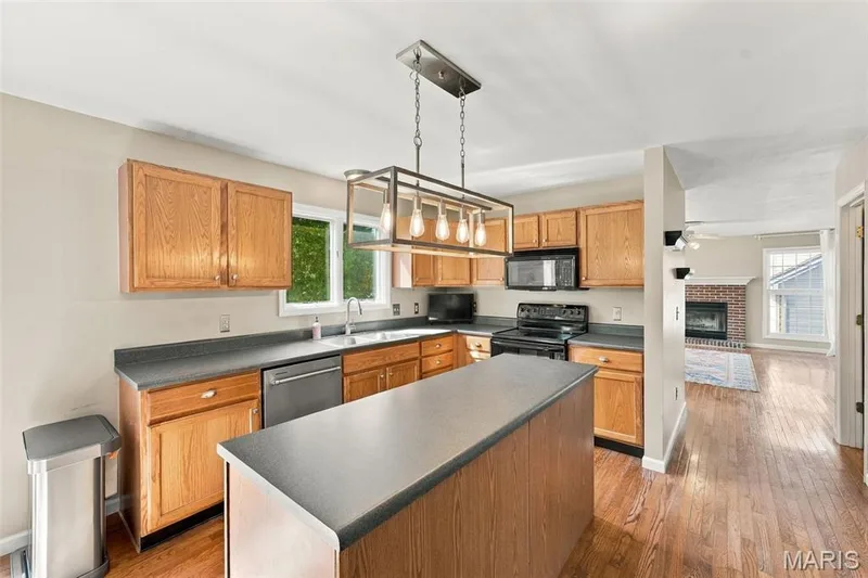Kitchen featuring wood-finish cabinetry, dark countertops, a center island, and stainless steel appliances — 8 Jacobs Place Court, O'Fallon, MO 63376