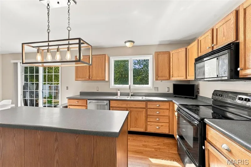 Wood-finish flooring, wood cabinetry, and grey countertops — 8 Jacobs Place Court, O'Fallon, MO 63376