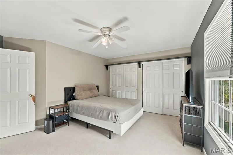 Wall-to-wall carpeting, ceiling fan with light fixture, window with blinds, and white paneled doors — 8 Jacobs Place Court, O'Fallon, MO 63376