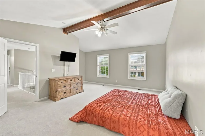 Vaulted ceiling with exposed wood beam, ceiling fan, carpeted flooring, and multiple windows — 8 Jacobs Place Court, O'Fallon, MO 63376