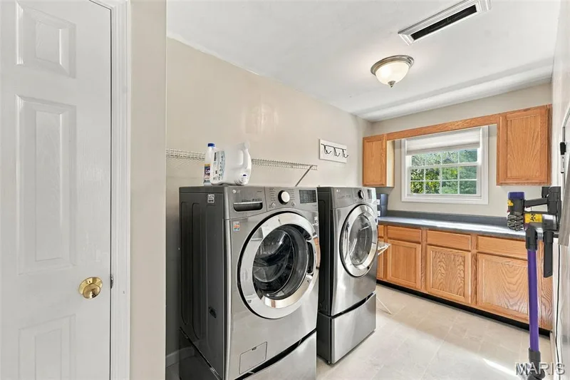Laundry area featuring a window, wood cabinetry, countertop space, and overhead lighting — 8 Jacobs Place Court, O'Fallon, MO 63376