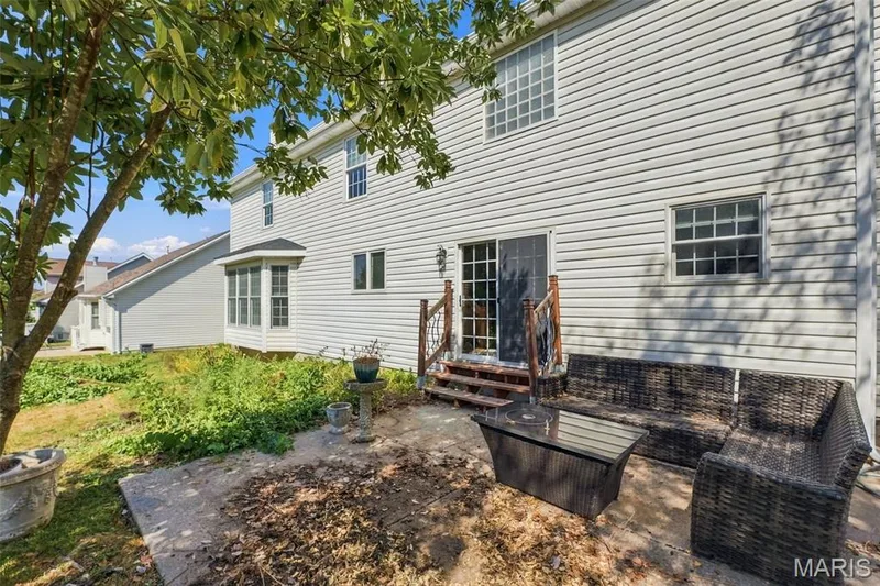 Exterior featuring white vinyl siding, a bay window, a sliding glass door, and an upper-level window with grid patterns — 8 Jacobs Place Court, O'Fallon, MO 63376
