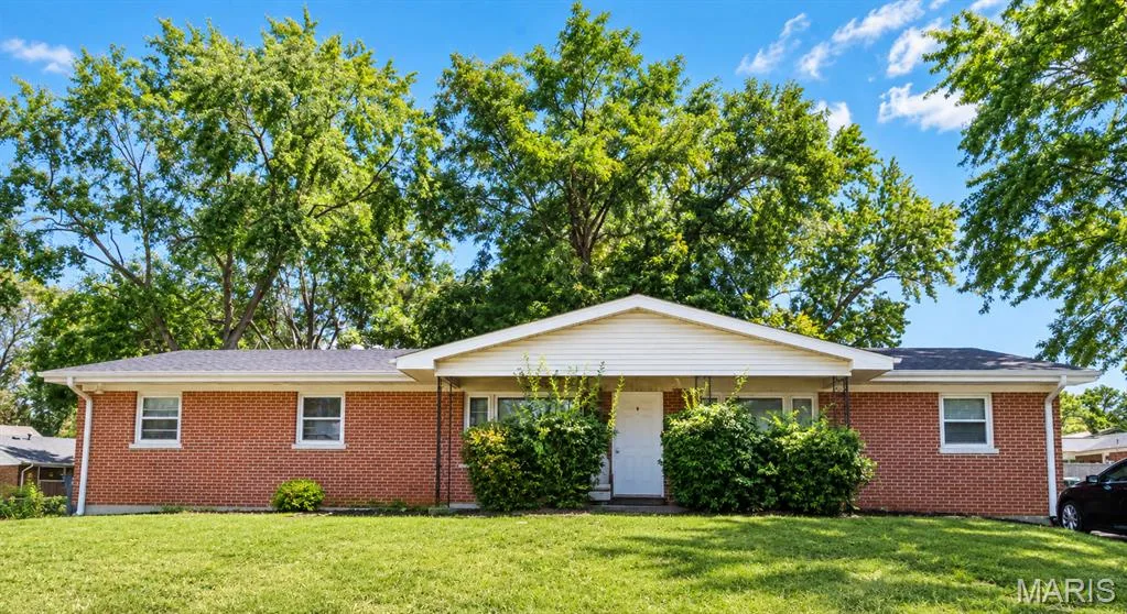 Red brick exterior with white trim, a covered porch, a gabled roof, and a mature treed backdrop — 908-910 Cole Boulevard, St Charles, MO 63301