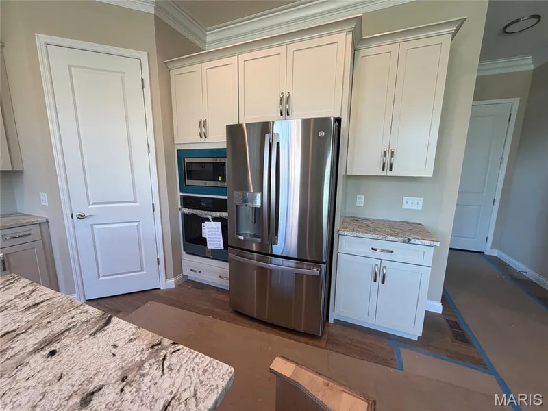 Kitchen featuring light-toned cabinetry, stainless steel appliances, built-in microwave, double oven, and granite countertops — 1000 Bellevaux Place, St Charles, MO 63301