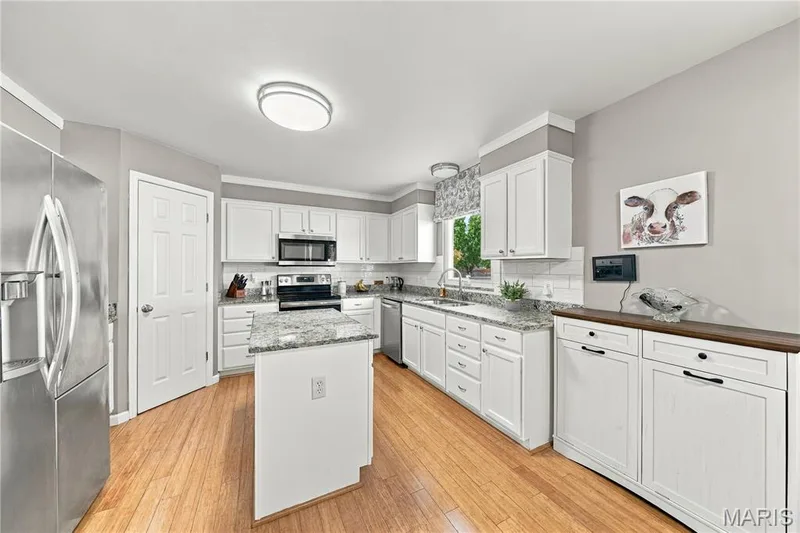 Updated casement window, wood floors, white cabinetry, granite countertops, walk-in pantry and neutral decor. — 1417 Plantation Manor Court, St Peters, MO 63303