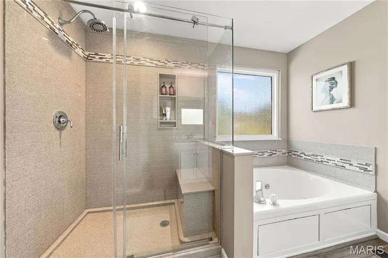 Updated privacy-glass picture window, luxury vinyl plank flooring, spacious shower with seat and glass surround, jetted tub and neutral decor. — 1417 Plantation Manor Court, St Peters, MO 63303