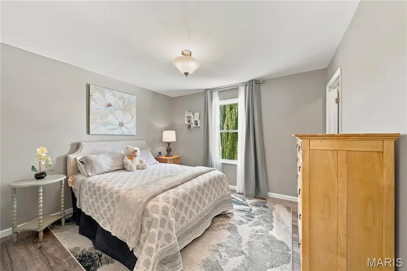 Corner bedroom with updated double hung window, luxury vinyl plank flooring, ceiling light, walk-in closet and neutral decor. — 1417 Plantation Manor Court, St Peters, MO 63303