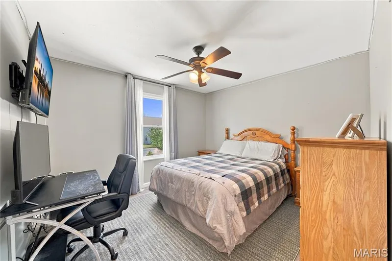 Middle bedroom with updated double hung window, luxury vinyl plank flooring, lighted ceiling fan, walk-in closet and neutral decor. — 1417 Plantation Manor Court, St Peters, MO 63303