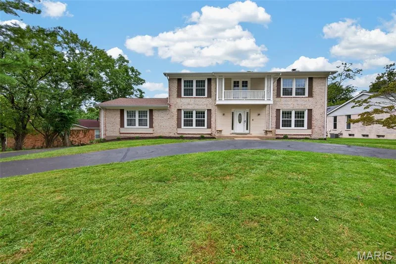 Brick veneer exterior with a prominent white entry door, upper-level balcony, and dark-stained window shutters — 231 Renaldo Drive, Chesterfield, MO 63017