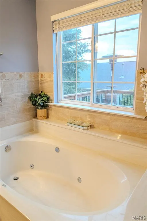 Jetted tub featuring a tiled surround and a large window with privacy blinds — 979 Bentley Park Circle, O'Fallon, MO 63368