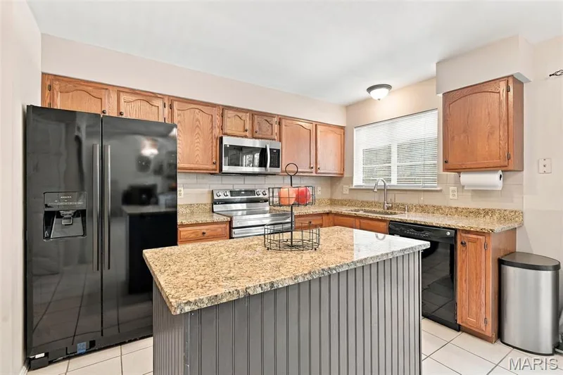 Kitchen with Center Island, Granite Counters, 2- yr new stove and microwave, views of the back yard — 5872 Wellington Farm Drive, St Charles, MO 63304
