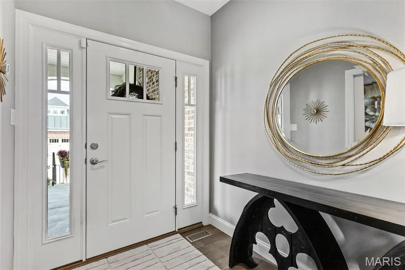 Entryway featuring a paneled door with transom and sidelight windows, light wood-finish flooring, and a decorative console table — 17028 Fire Glow Drive, Ballwin, MO 63011