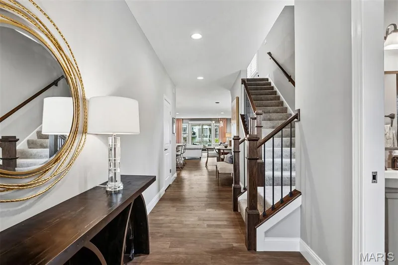 Wood-finish flooring, staircase with dark wood handrail and black iron spindles, recessed lighting, and white trim — 17028 Fire Glow Drive, Ballwin, MO 63011
