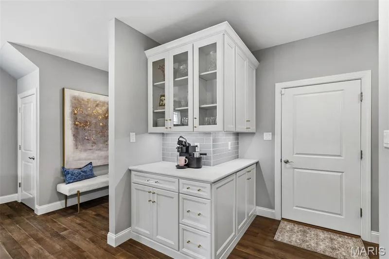 White cabinetry with glass-front upper doors, light-toned countertop, subway tile backsplash, and wood-finish flooring — 17028 Fire Glow Drive, Ballwin, MO 63011