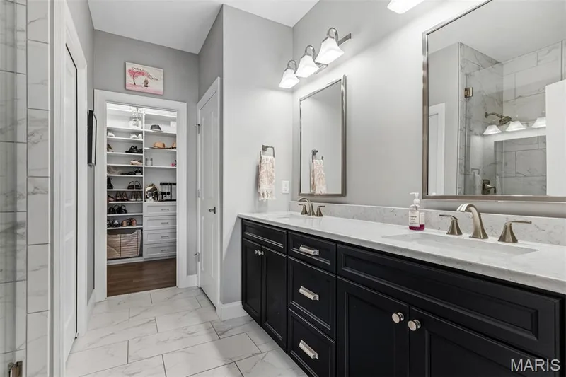 Dual vanity with black cabinetry and light-toned countertops, large framed mirrors, and brushed nickel fixtures — 17028 Fire Glow Drive, Ballwin, MO 63011
