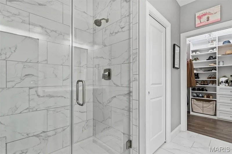 Glass-enclosed shower with a rainfall showerhead, tiled walls, and a built-in shelf — 17028 Fire Glow Drive, Ballwin, MO 63011