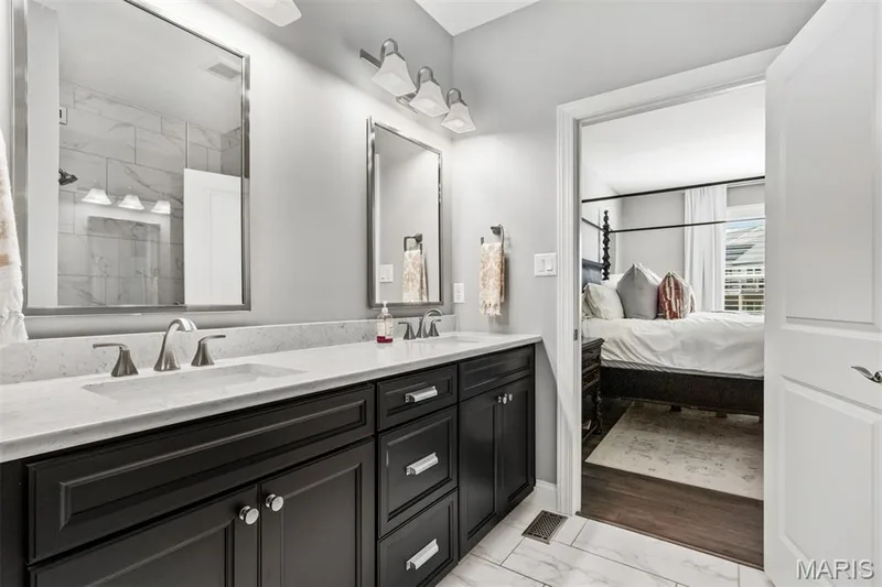 Dual sink vanity with quartz countertop, dark wood-finish cabinetry, brushed nickel hardware, and two framed mirrors — 17028 Fire Glow Drive, Ballwin, MO 63011