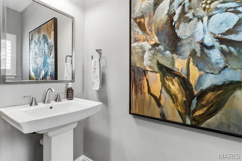Pedestal sink with a wide basin, polished chrome faucet, and a rectangular wall mirror — 17028 Fire Glow Drive, Ballwin, MO 63011