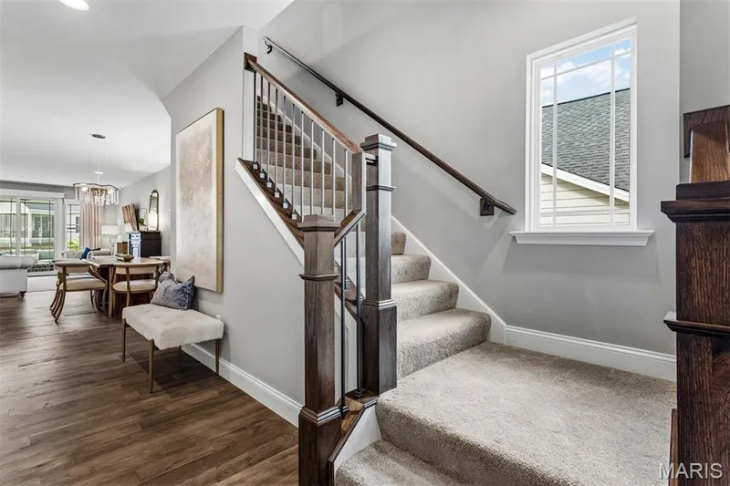 Staircase with wood-finish newel posts and handrails, white balusters, and carpeted treads — 17028 Fire Glow Drive, Ballwin, MO 63011