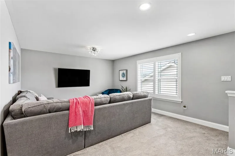 Recessed lighting, wall-mounted television, window with plantation shutters, carpet flooring, and a contemporary ceiling fixture — 17028 Fire Glow Drive, Ballwin, MO 63011