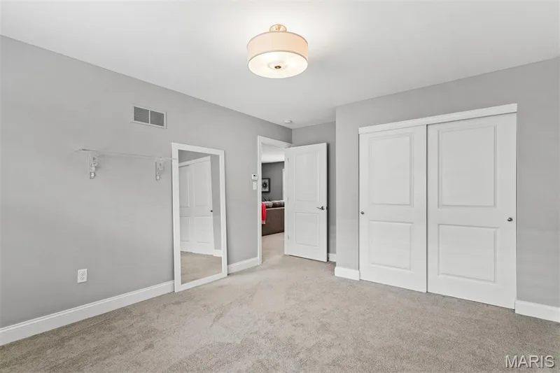 Plush carpet flooring, neutral paint palette, white trim, sliding panel doors, and overhead drum light fixture — 17028 Fire Glow Drive, Ballwin, MO 63011